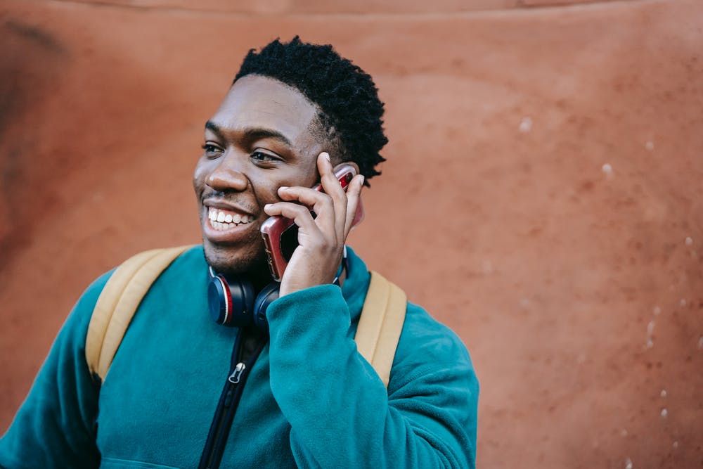 A man smiling whilst talking on a mobile phone.